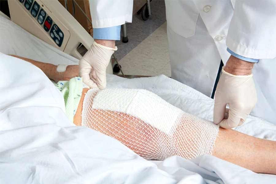 Wound care provider fixing bandage on patient's knee